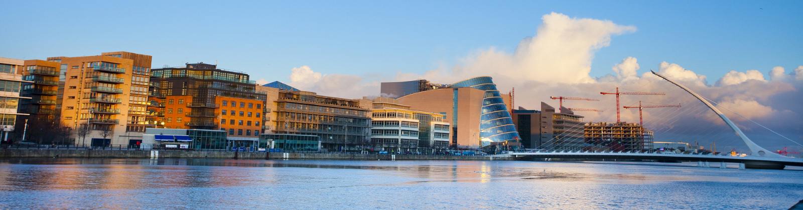 Sunny evening at Dublin Liffey quay with new harp bridge od the right Sunny evening at Dublin Liffey quay with new harp bridge od the right